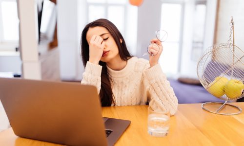 pretty girl with lond black hair is working on her laptop and sitting at home at the table